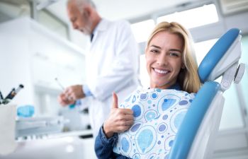 Woman dental patient with a perfect smile showing her thumb up.