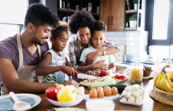 Happy Afro-American family: parents with a daughter and son cooking together