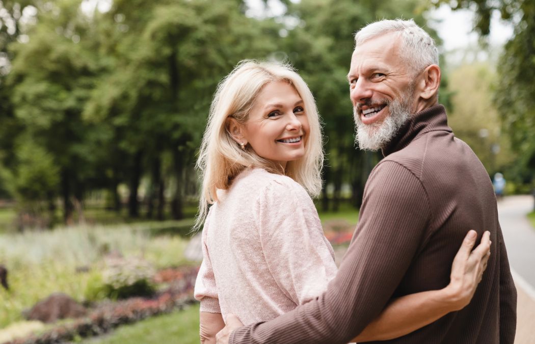 happily senior couple with perfect smiles walking in a park