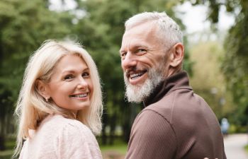 happy senior couple with beautiful smiles walking in a park