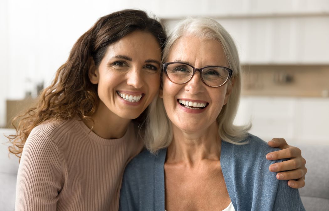 an adult woman and her senior woman showing perfect teeth in their smiles